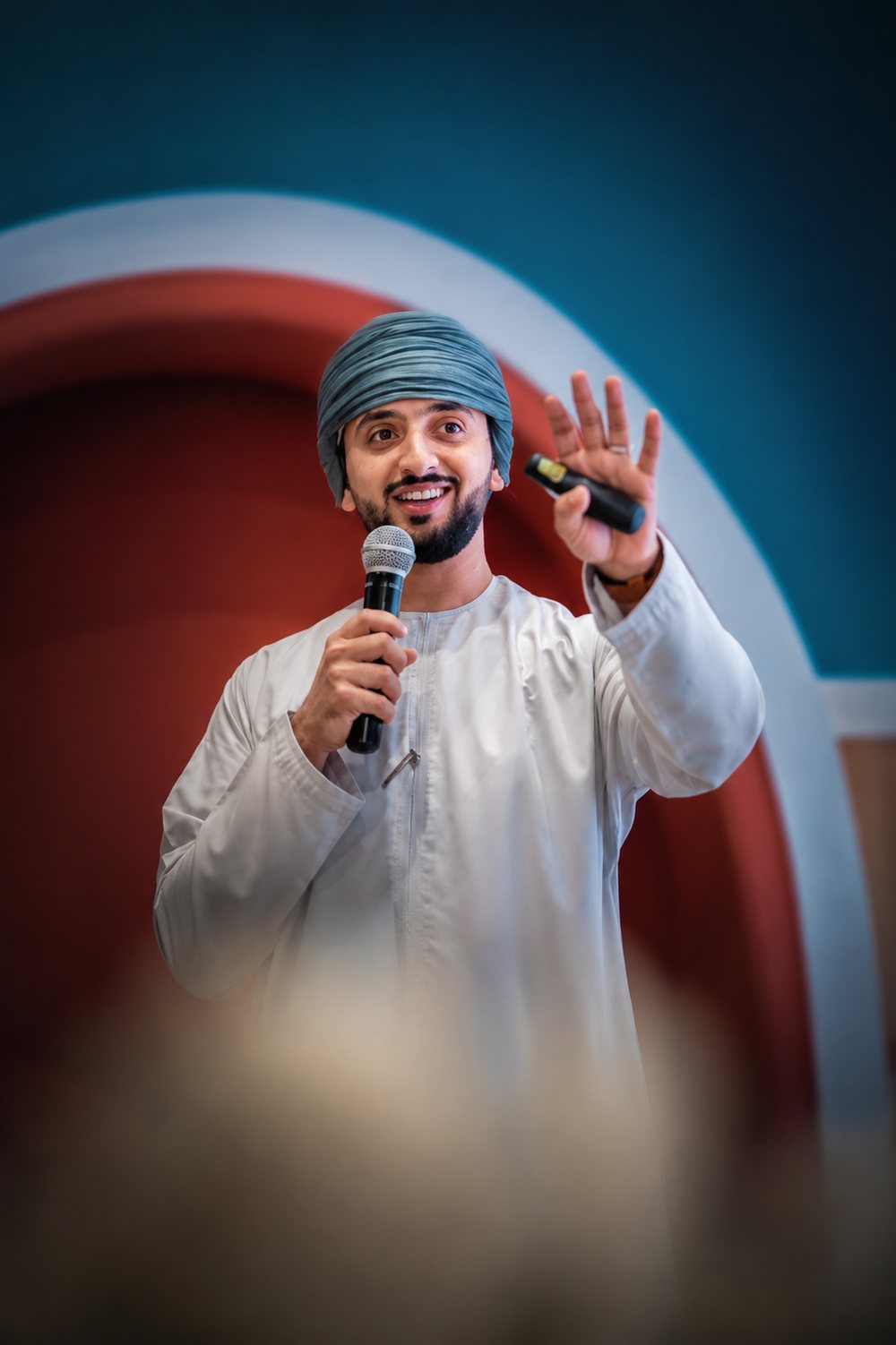 Saif Al Manji smiling while speaking with a microphone